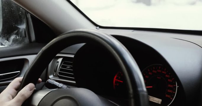 Closeup of person hands on steering wheel driving car. Man driving a vehicle.