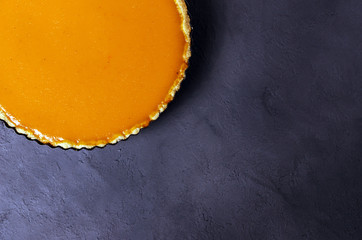 Fresh homemade pumpkin pie on dark stone background.