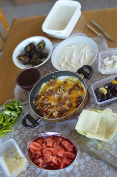 Traditional Turkish Country Breakfast with Turkish sausage and egg, sliced tomato, fresh and organic green pepper, butter, black olives, cheese, jam, milk cream and tea 