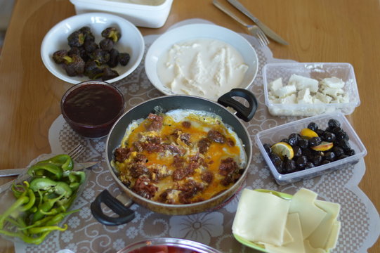 Traditional Turkish Country Breakfast with Turkish sausage and egg, sliced tomato, fresh and organic green pepper, butter, black olives, cheese, jam, milk cream and tea 