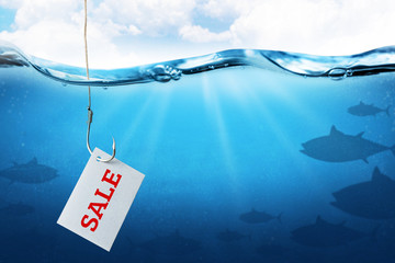The inscription sale on the sheet as bait for buyers. Fishing hook with fish bait as symbol of deception. Blue underwater sea background. - obrazy, fototapety, plakaty