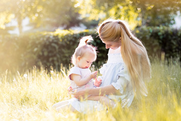 Happy family outdoors. Mother with baby, laughing and playing in the summer day on the nature
