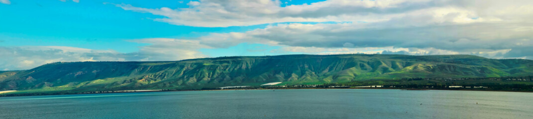 Golan Heights and Tiberian Lake panorama where green hills, blue sky with clouds