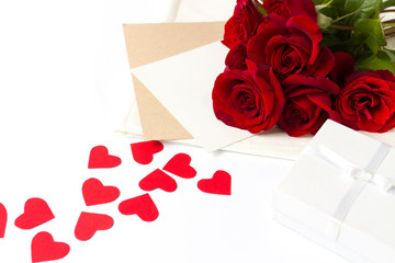 Bouquet of red roses and an envelope with a note, red hearts made of cardboard on a white background. Concept of a romantic gift for a loved one. Wedding themes