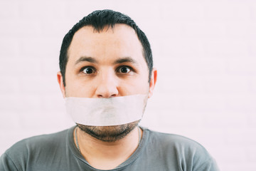 Angry man mouth covered by masking tape