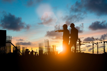 Silhouette of engineer and construction team working at site over blurred background for industry...