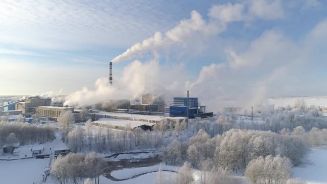 Aerial view of white smoke rising from cellulose factory on cold winter day