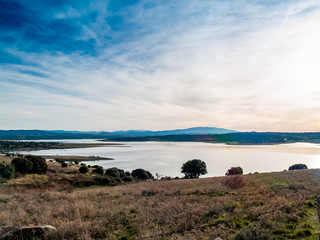 Landscape of a reservoir and mountains in a day with fog and clouds and birds swimming and flying in in La Maya Reservoir (Salamanca)