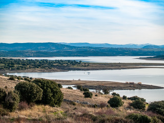 Landscape of a reservoir and mountains in a day with fog and clouds and birds swimming and flying in in La Maya Reservoir (Salamanca)