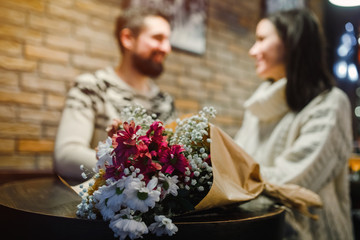 Couple with bouquet of flowers in coffee shop