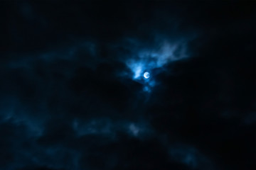 The white moon in the dark blue clouds of night.