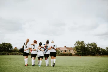 Tuinposter Female football players huddling and walking together © Rawpixel.com