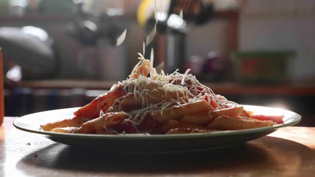 Sprinkle pasta with grated cheese in slow motion