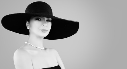 Retro black and white portrait of beautiful woman in classic hat and pearls jewelry