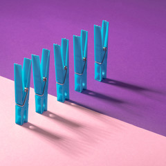 Blue clothespins with shadows on a pink purple background. Modern conceptual art.