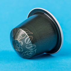 Green coffee cup with leaves on a blue background. Modern conceptual art