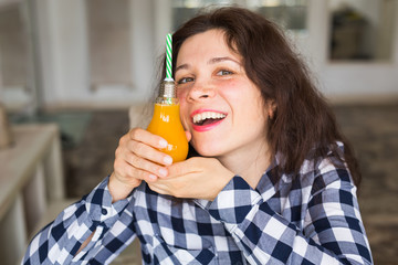 Detox, diet and healthy lifestyle concept - young woman holds a bottle of fresh juice