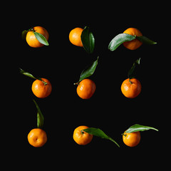 tasty orange tangerines with green leaves isolated on black