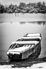 Naklejka premium Beautiful frozen river. A boats covered with snow. Black white photo