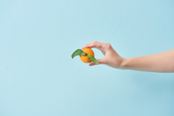 cropped view of woman holding tasty tangerine in hand isolated on blue