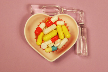 Pharmaceutical medicament, cure in container for health and heart on pink background.