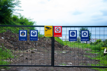 Fenced construction site with warning signs about work in progress.
