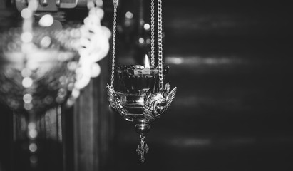 burning light in an old copper church lamp with the image of an angel, black and white photo