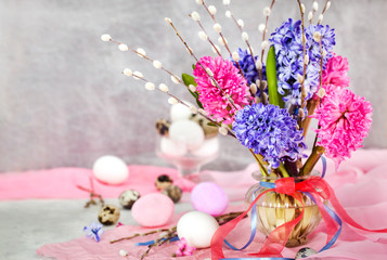 Easter eggs with beautiful hyacinths and willow bouquet on light background, spring holiday concept