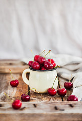 Fresh ripe cherries in a mug on rustic background