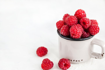 Fresh ripe raspberries in a mug on white