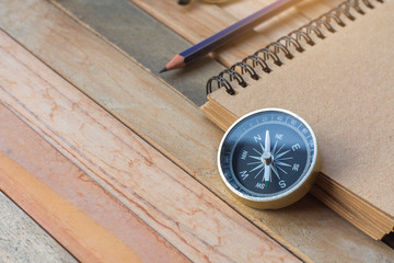 Compass, Notepad with pencil on wood board background.using wallpaper for education