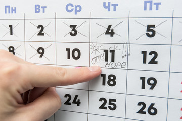 Hand indicates the day on the calendar with the inscription vacation