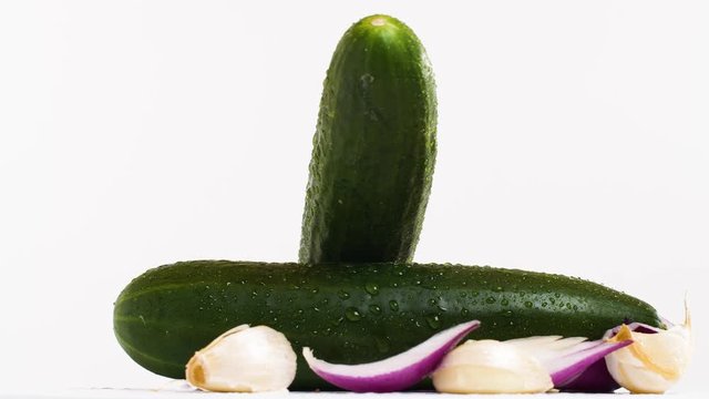 Fresh green cucumber with pieces of onion and garlic on a rotating plate