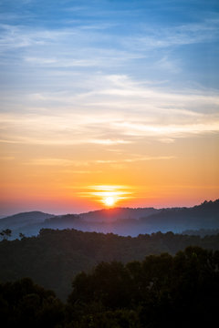 Fototapeta golden sunrise in the blue sky over silhouette of mountains