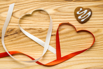 Concept Valentine's Day. Heart-shaped tapes with handmade heart-shaped cookies with the pattern of the glaze on a wooden table. Top view. Copy space.