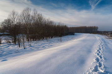 Path in the snow showing footsteps in winter time in sunset, low temperature, in the forest