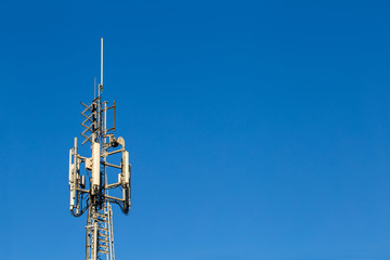 Telecom tower lit by sun on a bright blue sky