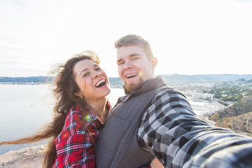 Obraz premium Travel, vacation and holiday concept - Happy couple taking selfie over beautiful landscape