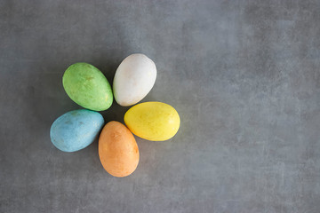 Five multicolored decorative eggs on a gray background. Top view.