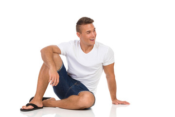 Fototapeta premium Cheerful Casual Man In White Shirt Sitting On Floor And Talking
