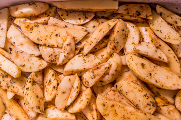 image of potatoes sliced and seasoned with spices and oil to be baked