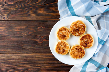 Cottage cheese pancakes on dark wooden background.