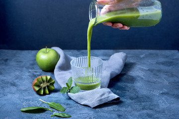 Green smoothie pouring into glass, detox vitamin drink with spinach, kiwi, avocado, apple, healthy lifestyle - 246141184