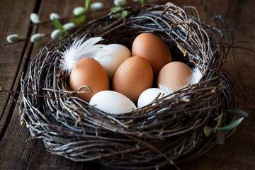 Easter eggs in a nest on dark rustic wooden background