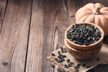 Pumpkin seeds on wooden background, healthy vegan ingredient or snack, nutrition concept, copy space background