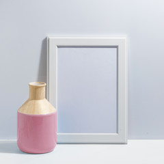 Mock up white frame and pink vase on book shelf or desk. Minimalistic concept.