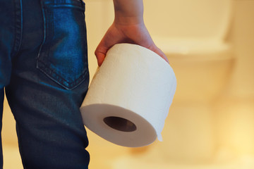 Rare view of kid holding toilet roll in the front of toilet, little boy suffers from diarrhoea holding toilet paper, Low view Child bringing roll of tissue walking to rest room, Children health care - obrazy, fototapety, plakaty
