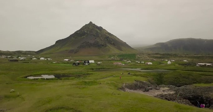 Aerial Footage of Moutain Over Wooden Houses and Lake During Cloudy Summer In Hellnar, Snaefellsness Peninsula, Iceland
