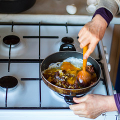 left side view of a hand which is cooking omelette with Turkish sausage. purposely blurred.
