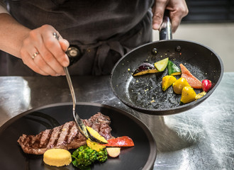 Chef puts the dish on a plate. Preparing to serve.